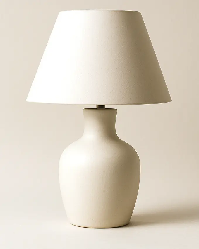 A cream ceramic table lamp on warm white paper.